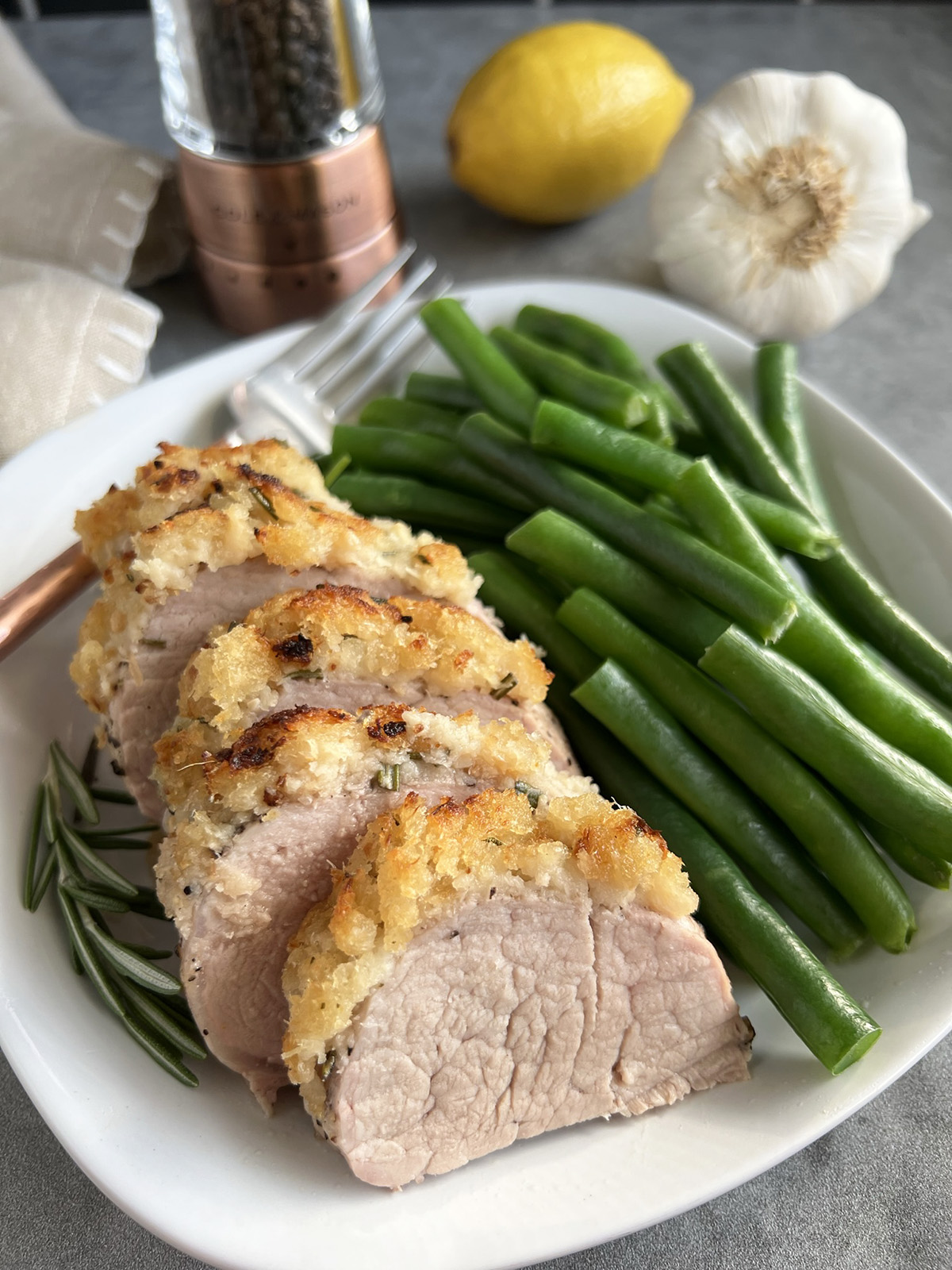 Low sodium horseradish crusted pork tenderloin served on a plate with green beans. 
