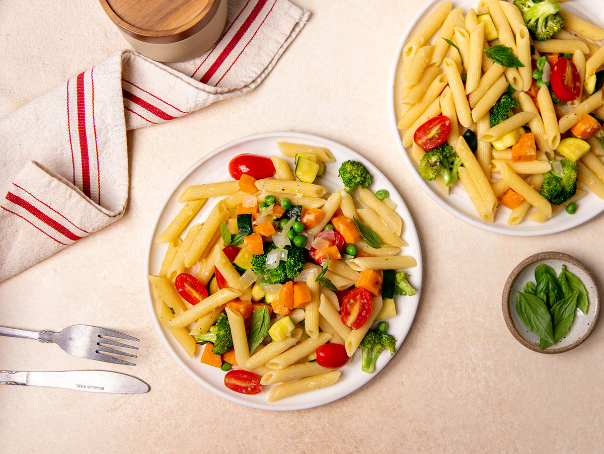 Two servings of low-sodium pasta primavera on white plates.