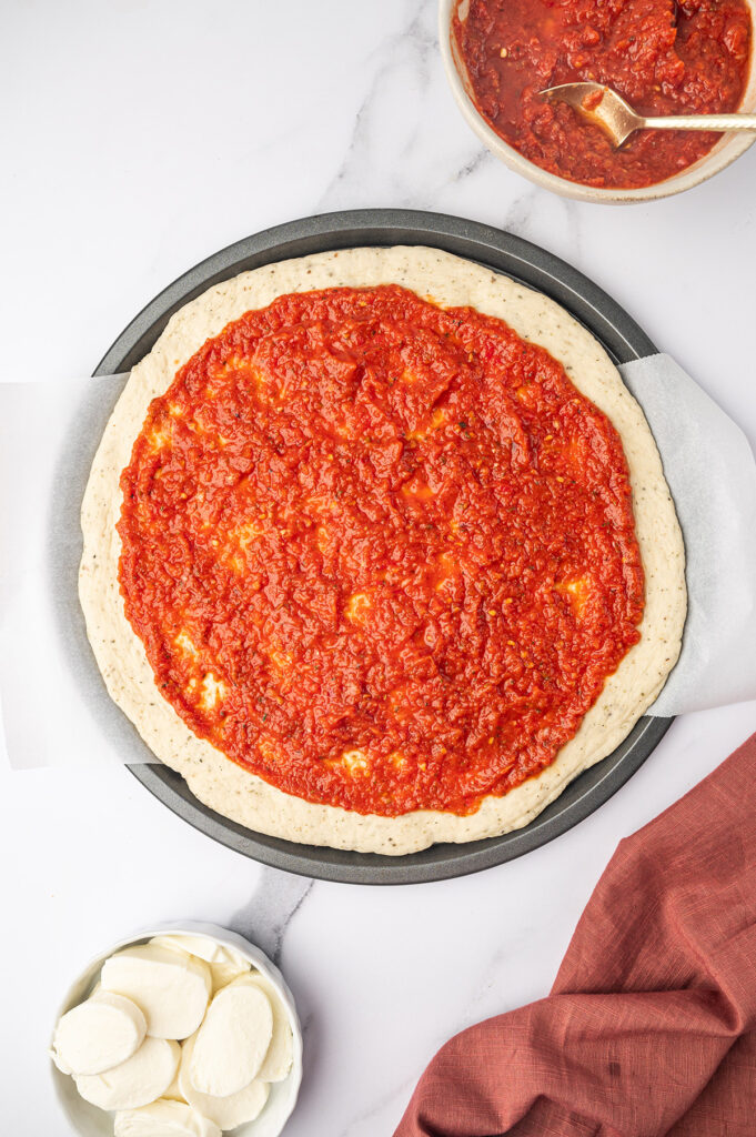 A layer of pizza sauce on pizza dough.