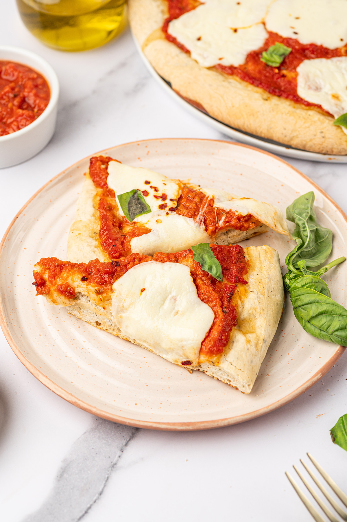 A white plate of Margherita pizza slices.
