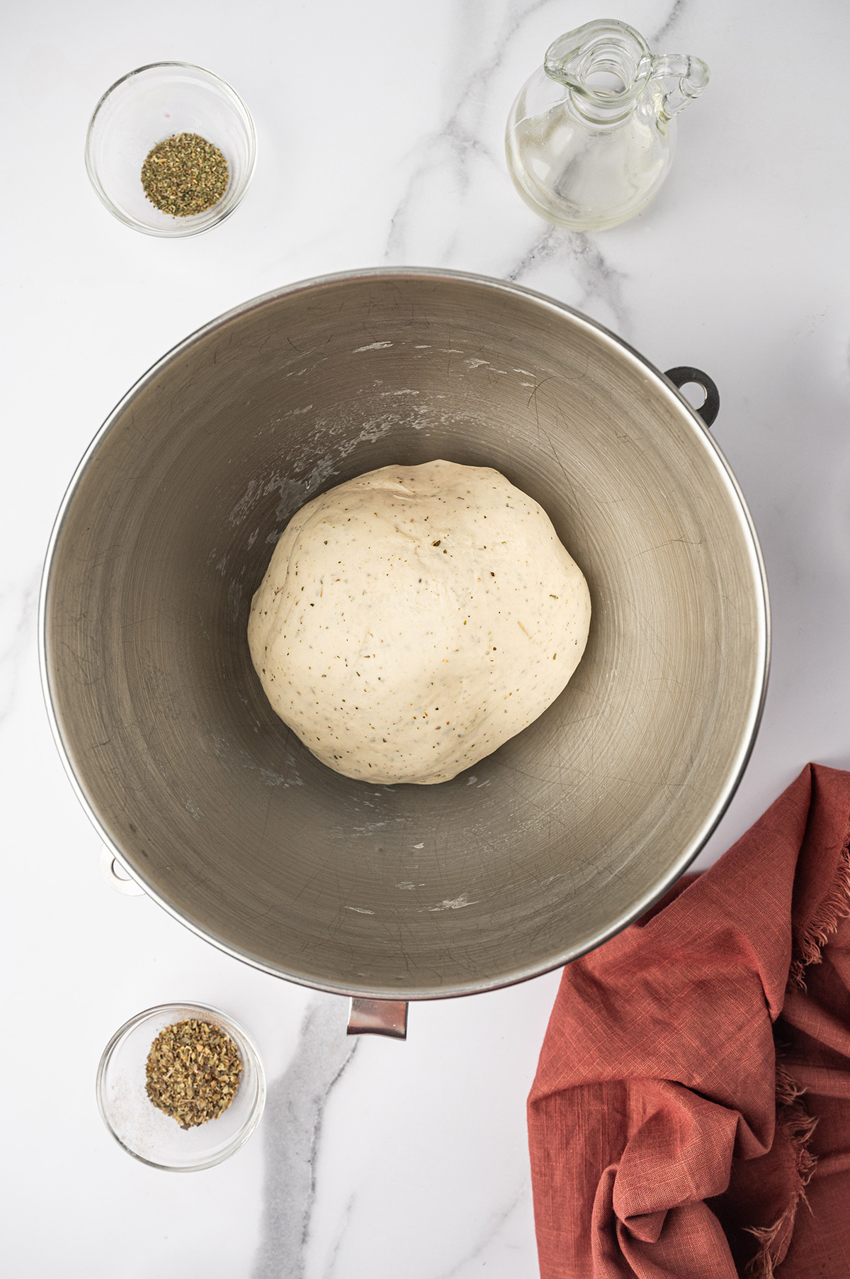 Pizza dough in a stainless steel bowl.