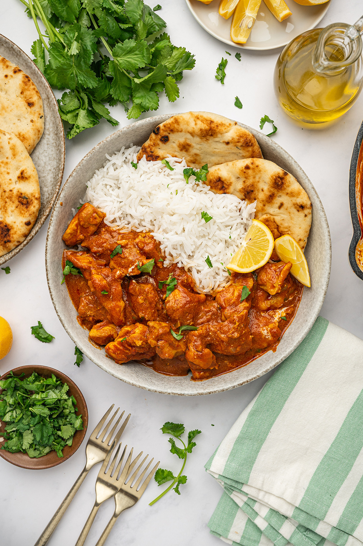 Low sodium butter chicken garnished with fresh parsley, served alongside a lemon wedge and a piece of naan bread.