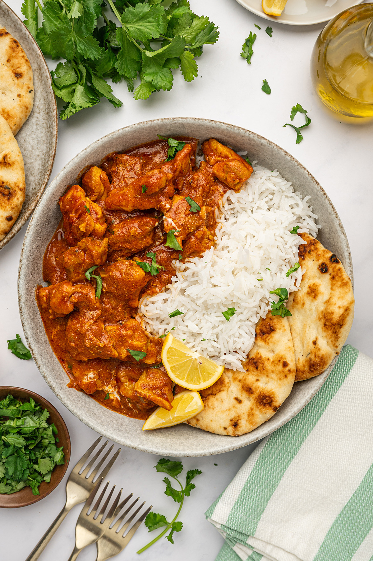 A bowl of low sodium butter chicken served with fluffy basmati rice, warm naan, and a lemon wedge on the side.