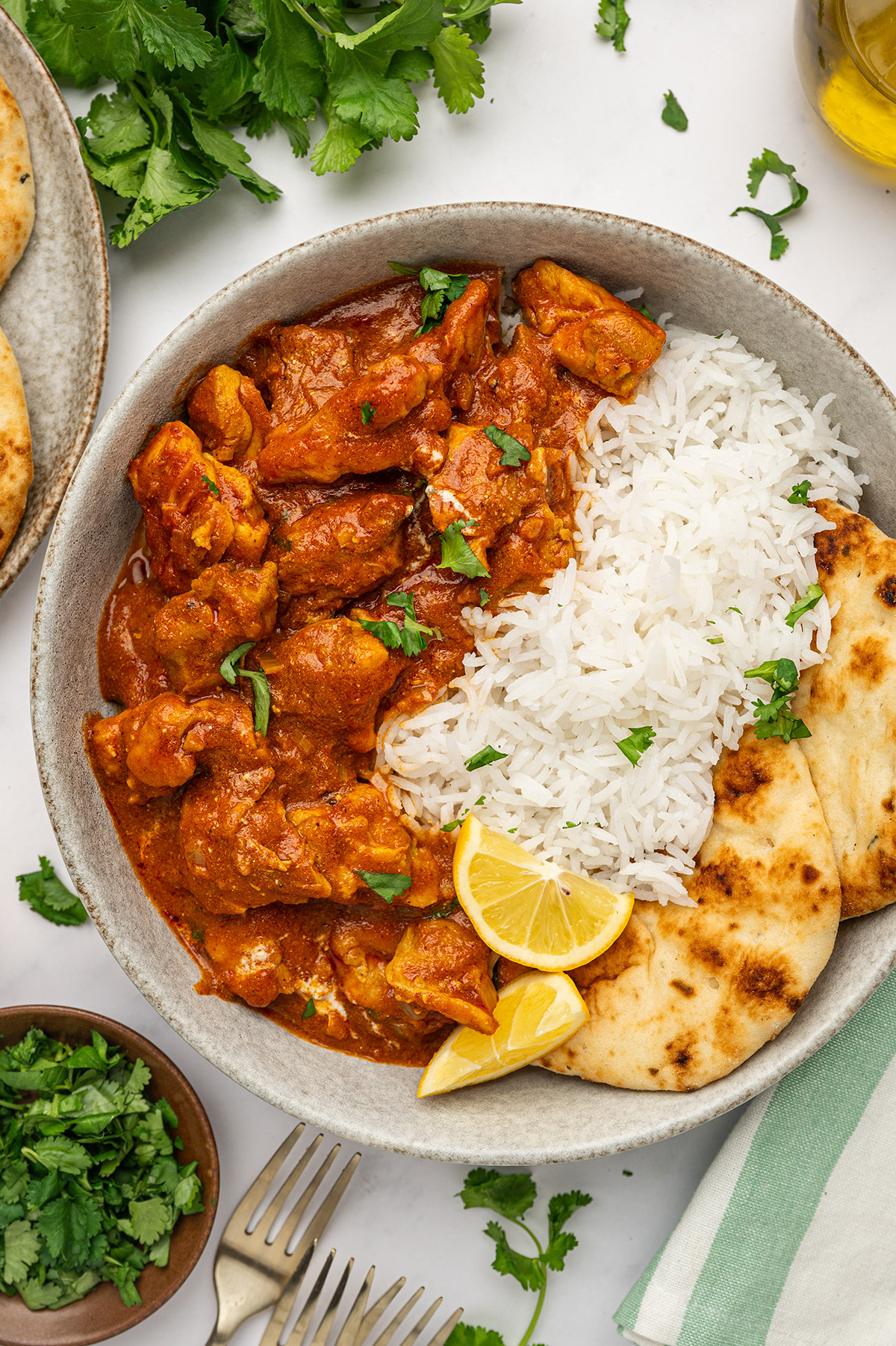 Low sodium butter chicken served on a plate with naan bread, a lemon wedge, and a side of basmati rice.