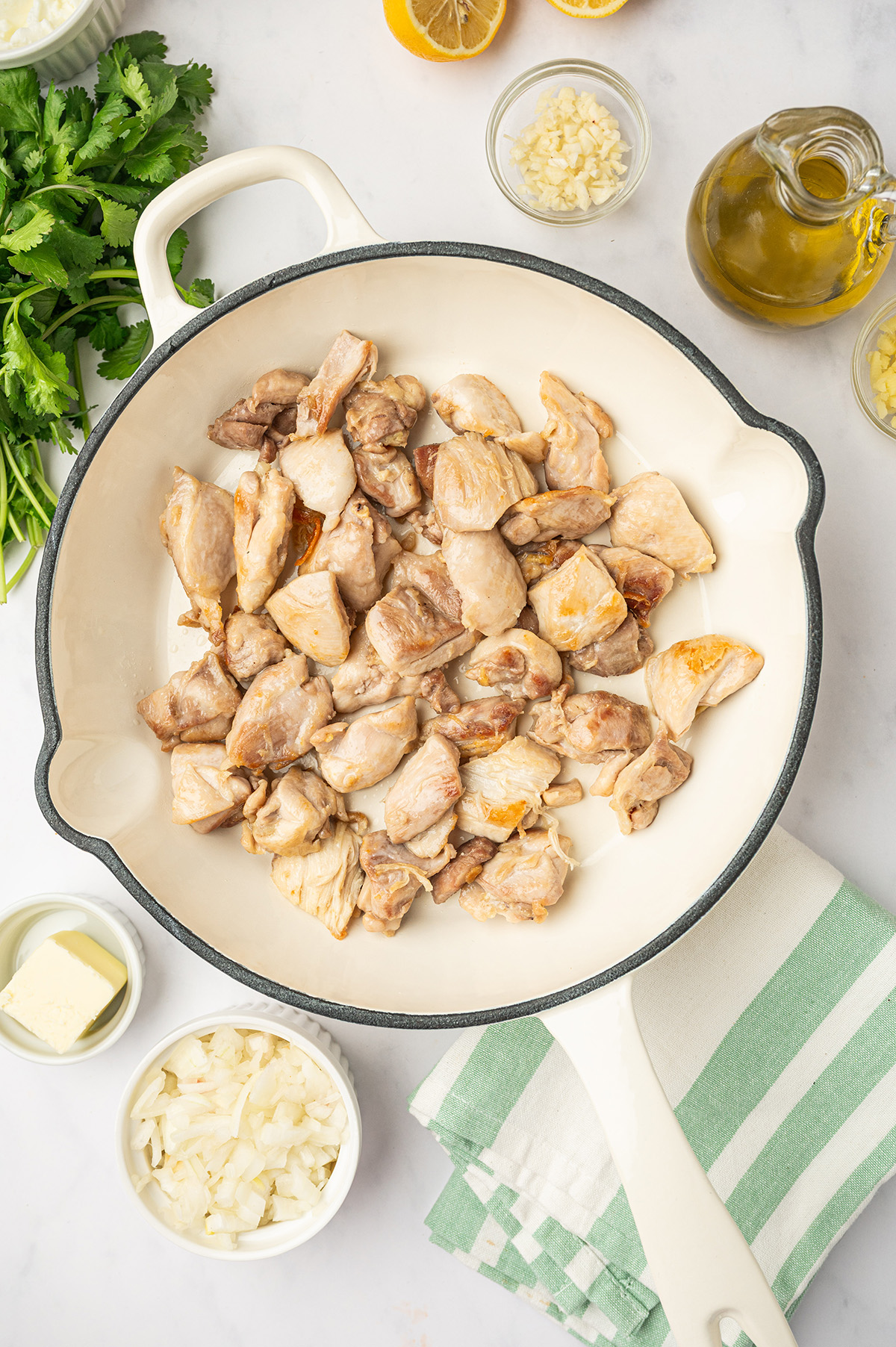 Chicken thigh pieces cooking in a skillet for low sodium butter chicken recipe.