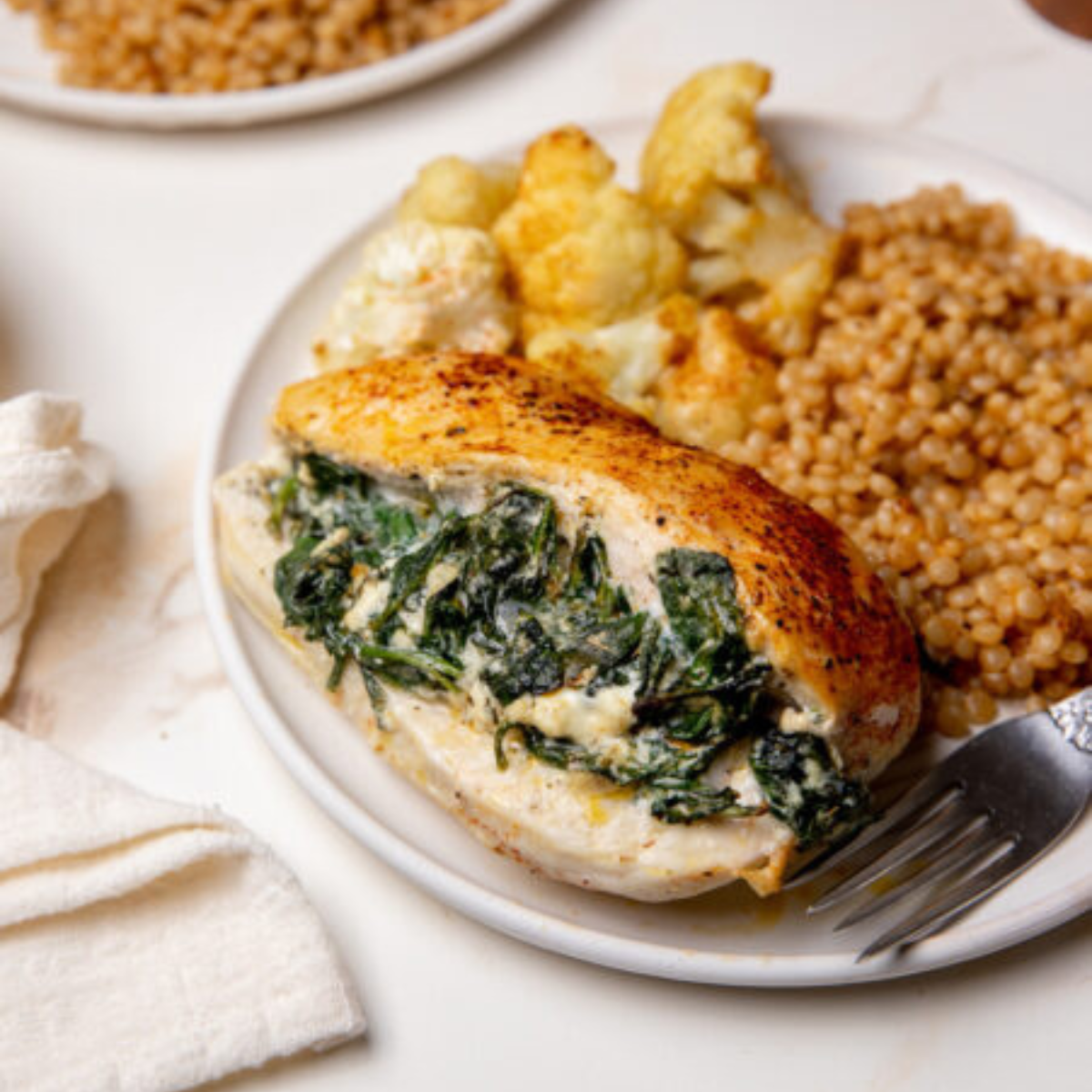 A serving of spinach stuffed chicken on a white plate.