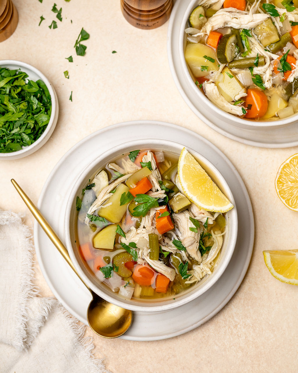 Two bowls of low sodium chicken and vegetable soup surrounded by ingredients.