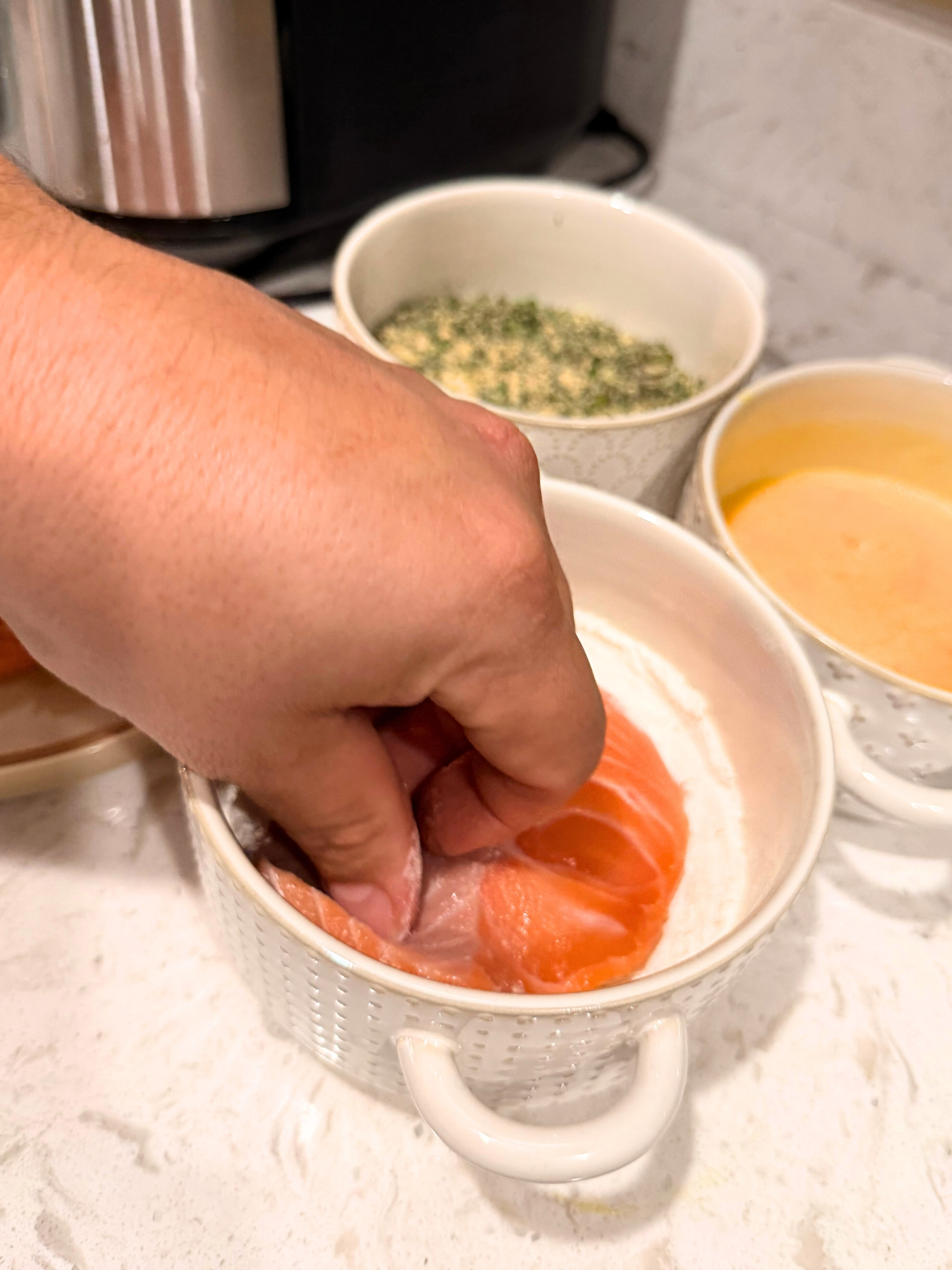 Dipping salmon in flour.