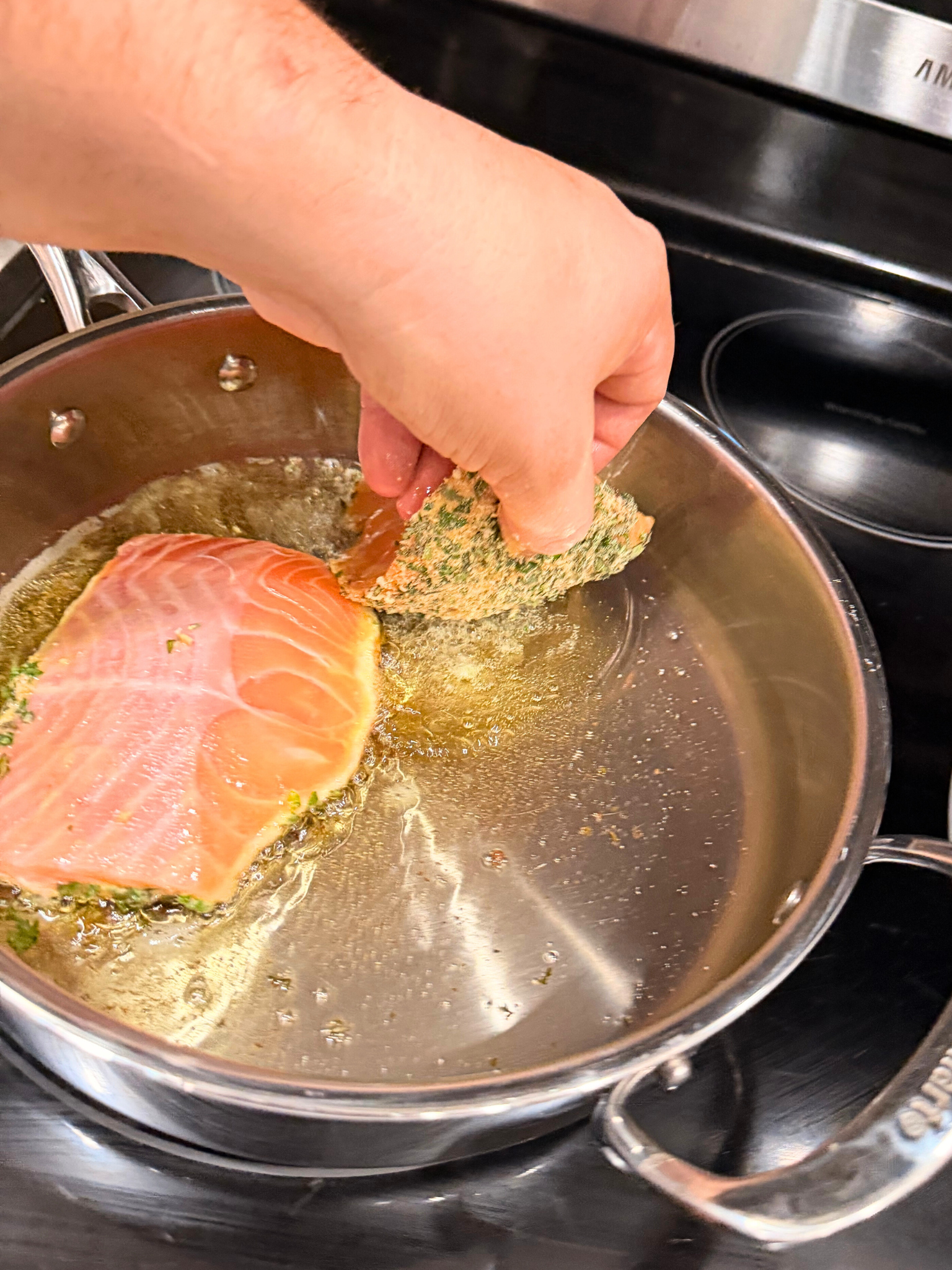 Adding salmon breadcrumb-side down in a pan to sear.